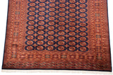 Vintage Bokhara rug corner, with intact navy selvage, white fringe, and rust geometric border.