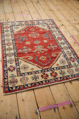 Angled perspective of a Pakistani Caucasian rug, showing its cherry red field and lustrous pile.