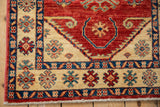 Corner detail of a Caucasian design rug highlighting the blue, red, and ivory floral border.