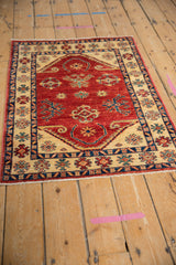 Pakistani rug with a Caucasian geometric design shown at an angle, emphasizing its lustrous red wool pile.