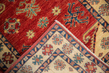 Folded corner of a Caucasian design rug contrasting the cherry red field with its ivory floral border.