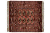 Ivory fringe detail on the dusty rose Bokhara rug, showing geometric gul medallions.