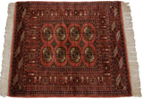 Dusty rose Bokhara rug corner with geometric gul medallions and fine borders.