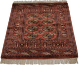 Corner detail of vintage Bokhara rug, showing hand-knotted fringe and gul motifs.