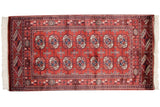 Detailed repeating gul medallions in wine red and navy on a finely woven Bokhara rug.