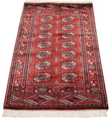 Angled view of a fine Bokhara rug highlighting the lustrous wool pile and repeating red and navy gul motif.