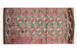 Symmetrical rows of detailed gul medallions on the plush, mallard green wool of a fine Bokhara rug.