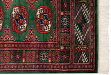 A finely woven gul medallion and detailed geometric border on a plush green vintage Bokhara rug.