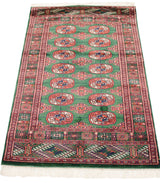 Vintage Bokhara rug at an angle, displaying its full length and lustrous mallard green wool pile.