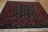 Angled perspective on the plush, high-sheen pile and detailed geometric borders of a vintage Bokhara rug.