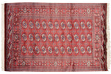Multi-column rows of geometric gul medallions on a wine red vintage Bokhara rug.