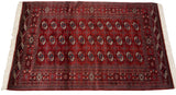 Angled view of a vintage Bokhara rug displaying its silk-like wool pile and tight gul medallions.