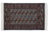 Vintage Bokhara rug featuring detailed gul medallions in navy and blush on a pale denim blue field.