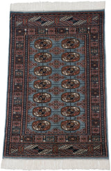 Vintage Bokhara rug from an angle, showing the repeating gul medallions on its lustrous denim blue pile.