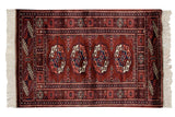 Detailed rows of geometric gul medallions in wine red, navy, and ivory on a vintage Bokhara rug.