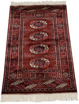 Vintage Bokhara rug mat displaying a tight, repeating gul pattern in deep red, navy, and ivory.