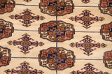 A close-up of the plush, silk-like pile showing detailed gul medallions in navy, ivory, and bronze.