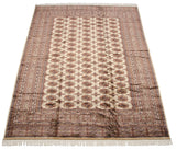 Angled view of a vintage Bokhara rug displaying the full gul pattern and lustrous wool pile.