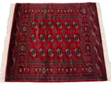 Cherry red vintage Bokhara rug showing detailed 'elephant footprint' gul medallions.