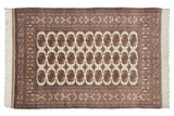 Overhead view of a vintage Bokhara rug's intricate grid of gul medallions in rust, brown, and navy.