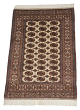 Angled perspective of a vintage Bokhara rug showing the lustrous wool pile and repeating gul medallions.