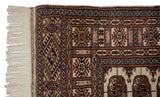 Corner of a fine Bokhara rug showing the intricate geometric border and original ivory fringe.