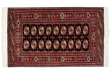 Vintage fine Bokhara rug with repeating red rust and ivory gul medallions on a black field.