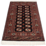 Angled perspective on a vintage Bokhara rug highlighting the lustrous pile and geometric gul design.