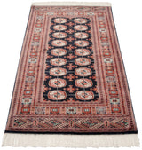 An angled view showcasing the fine weave and repeating gul medallions of a vintage Bokhara rug.