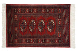 Vintage Bokhara rug with repeating geometric gul medallions in cherry red, navy blue, and ivory tones.