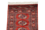 A close view of the vintage Bokhara rug's fine weave, detailed border, and intact ivory fringe.