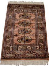 Vintage Bokhara rug with dusty rose gul medallion and geometric border patterns.