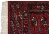 Plush red pile, secured edge, and clean ivory fringe on the corner of a vintage Bokhara rug.