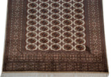 Intricate geometric border and soft ivory fringe of a plush vintage Bokhara carpet.