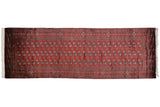 Vintage Bokhara runner showing repeating rows of gul medallions on a cherry red field.