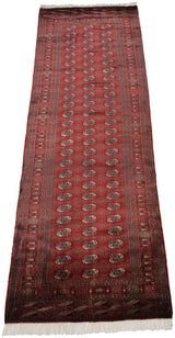 The long, repeating geometric pattern of a vintage Bokhara runner viewed from an angular perspective.