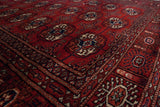 Angled view of the fine Bokhara rug corner showing the cherry red pile and navy gul medallions.