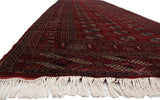 A long view down the fine Bokhara runner, showing its plush cherry red pile and repeating gul pattern.