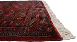 Angled view of the fine Bokhara rug's plush red pile, intact selvage, and ivory fringe.