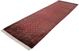 Angled full-length view of a vintage Bokhara runner showing its plush cherry red pile and fine weave.