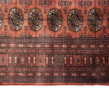 Vintage Bokhara carpet's intricate dusty rose, navy, bronze geometric borders and gul medallions.