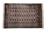 Vintage fine Bokhara rug with repeating geometric gul medallions in navy blue and bronze on a beige ground.