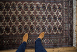 A person's perspective looking down at the repeating gul medallions of a plush vintage Bokhara rug.