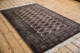 Angled view of a vintage Bokhara rug showing its repeating gul medallions and lustrous, plush pile.