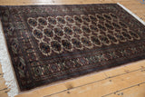 Angled view of a traditional Bokhara rug highlighting the lustrous pile and repeating gul design.
