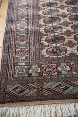 A vintage Bokhara rug's plush, full pile with intricate geometric borders and clean ivory fringe.