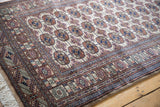 Angled view of a fine Bokhara rug corner, showing the lustrous pile and detailed gul motifs.