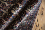 The plush, silk-like wool pile of a vintage Bokhara rug folded to show its high sheen.