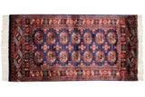 The detailed repeating gul medallions of a fine vintage Bokhara rug in navy and rust.