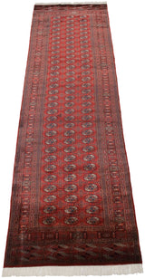 Angled view of a fine Bokhara runner's lustrous cherry red pile and repeating geometric gul medallions.